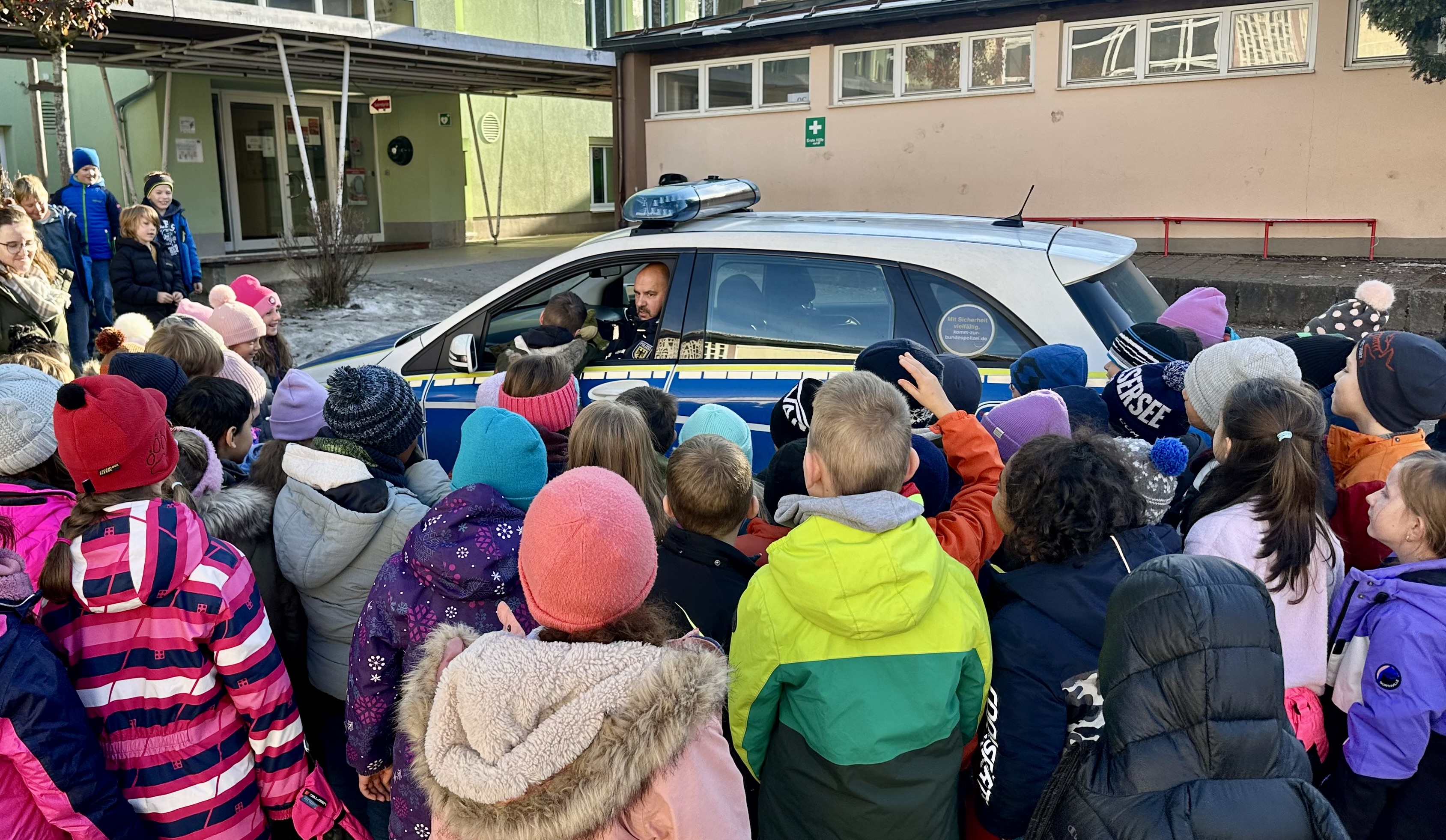 Große Gruppe von Kindern versammelt um das Polizeifahrzeug